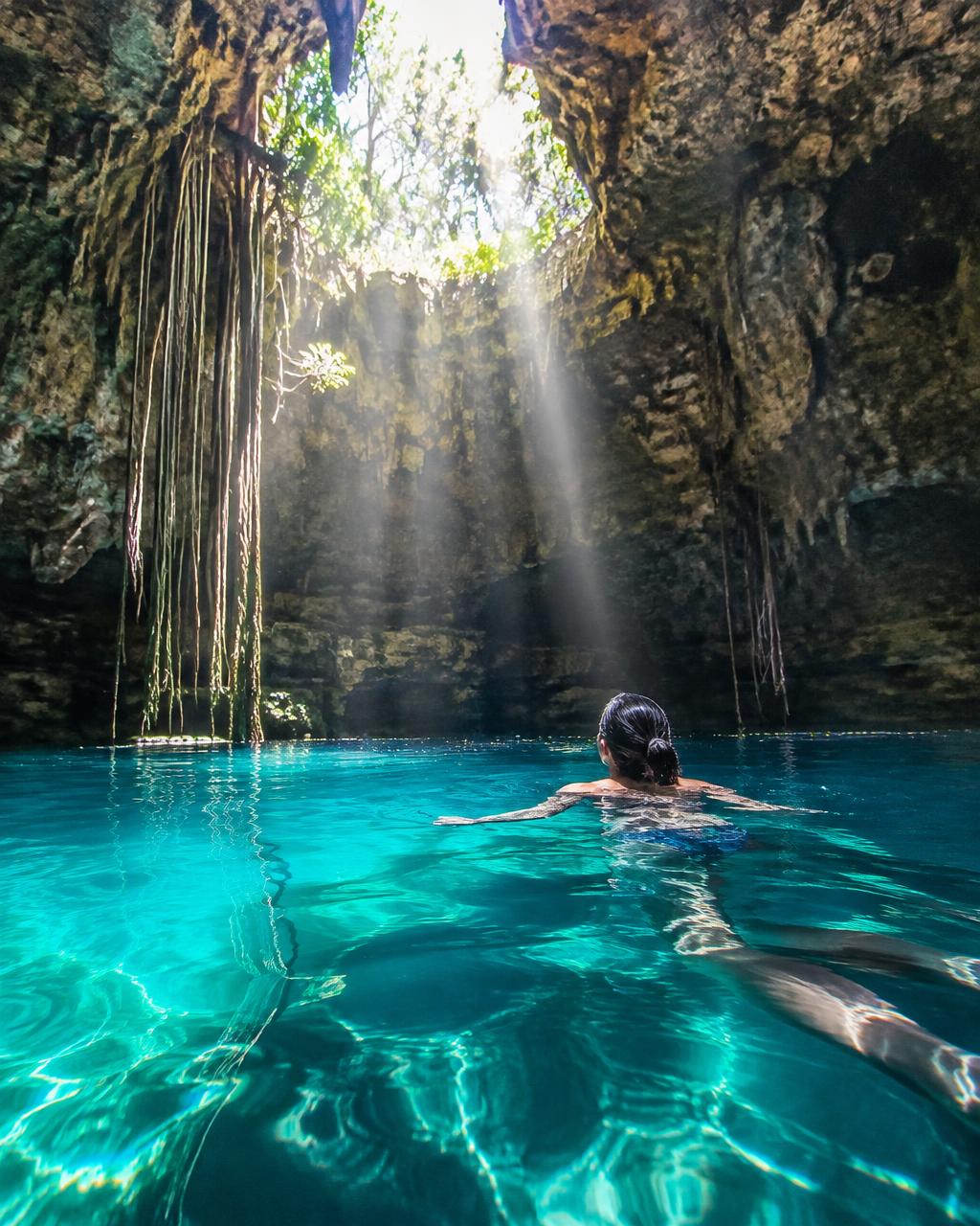 Viajera nadando en un cenote de aguas turquesa